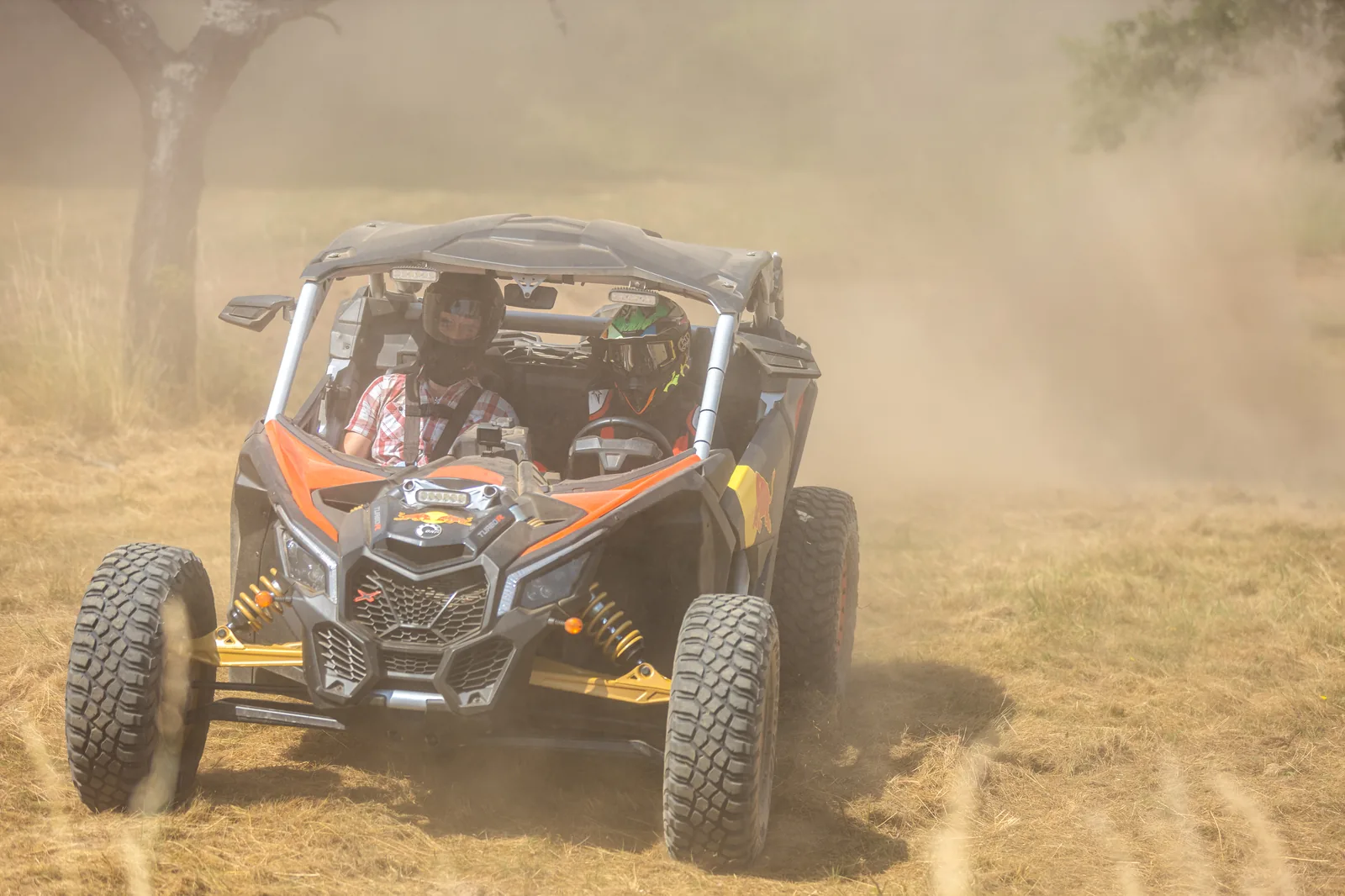 Dva jezdci s helmami společně v buggy v oblaku prachu